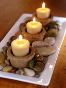 Stones that have been through polishing process are photographed with candles in a dish.