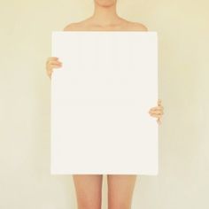 A person standing holding a blank poster in front of her.