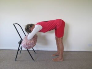 Yoga forward bend by eve using chair and bolster