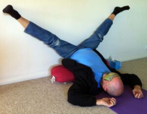 Photo of man lying down in yoga pose with legs in the splits on wall