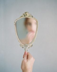 Image of person's hand holding a mirror with no reflection.
