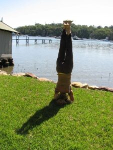 Image of eve in headstand by the water.