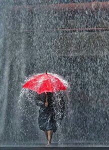 Image of girl in a hard rain with a red umbrella