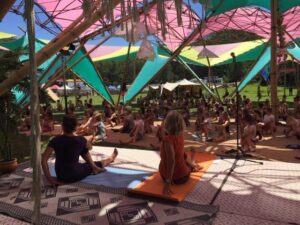 Eve teaching yoga at festival under big canopy