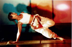 Eve in a photo of a one-arm balancing pose, her leg in lotus pose.