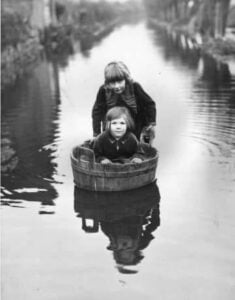 Photo of a person pushing along a boat with a child in it